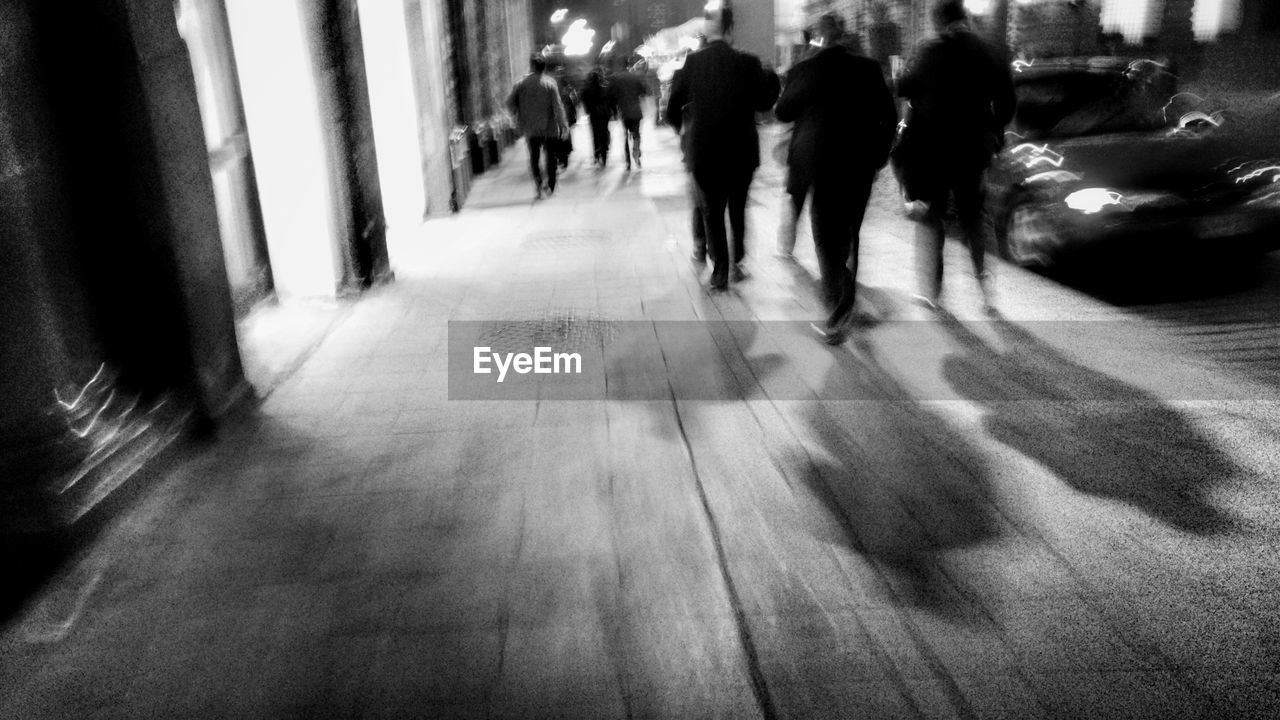 Rear view of people walking on footpath at night