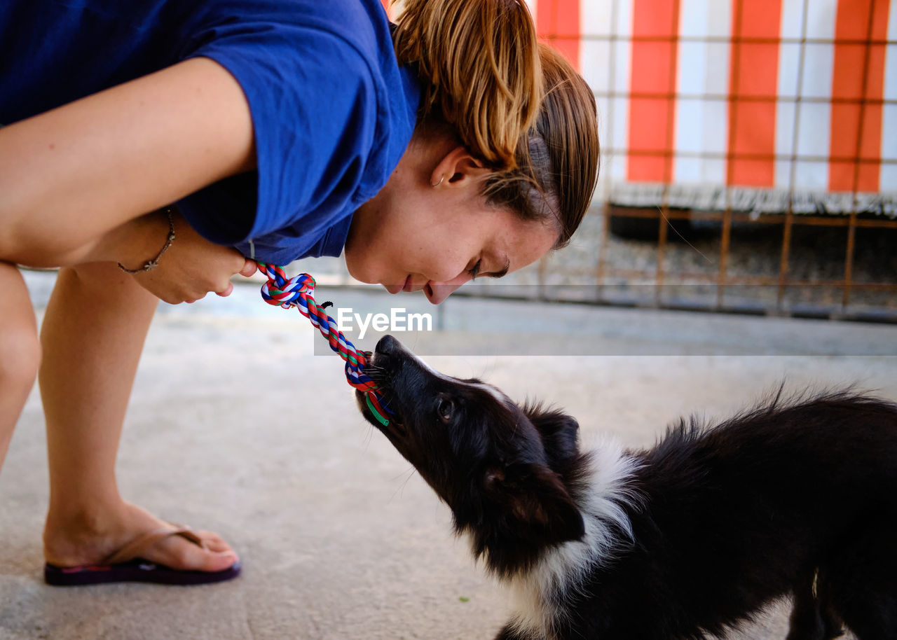 Side view of girl playing with dog