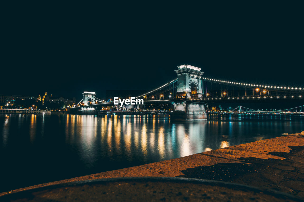 Illuminated chain bridge over river danube against clear sky at night
