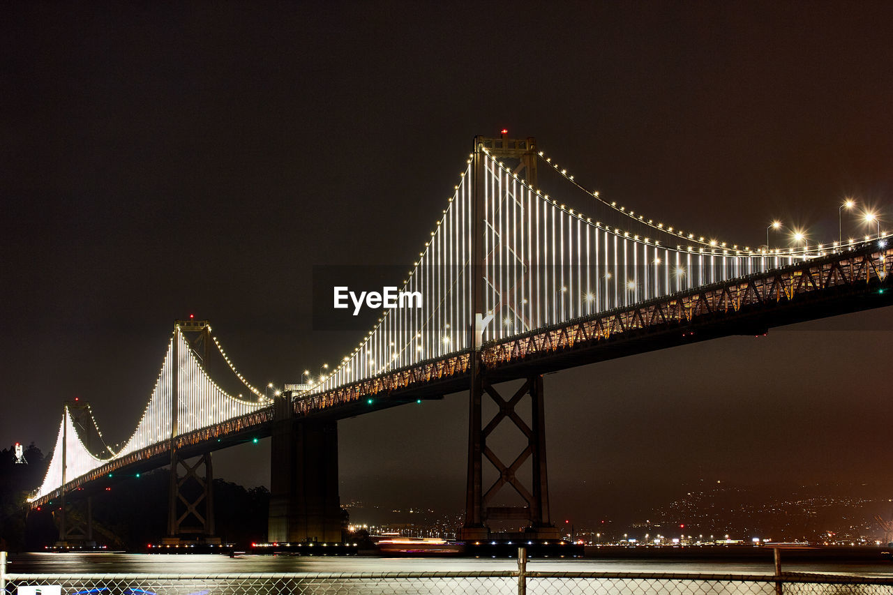 Low angle view of illuminated suspension bridge at night