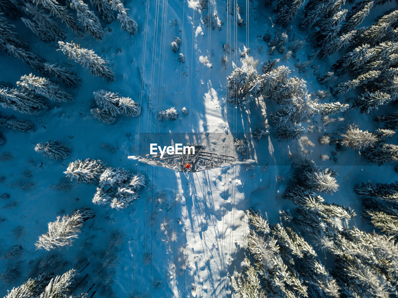 Directly above electrical pylon on snow covered land