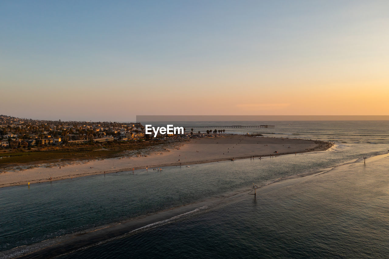 SCENIC VIEW OF BEACH AGAINST SKY AT SUNSET