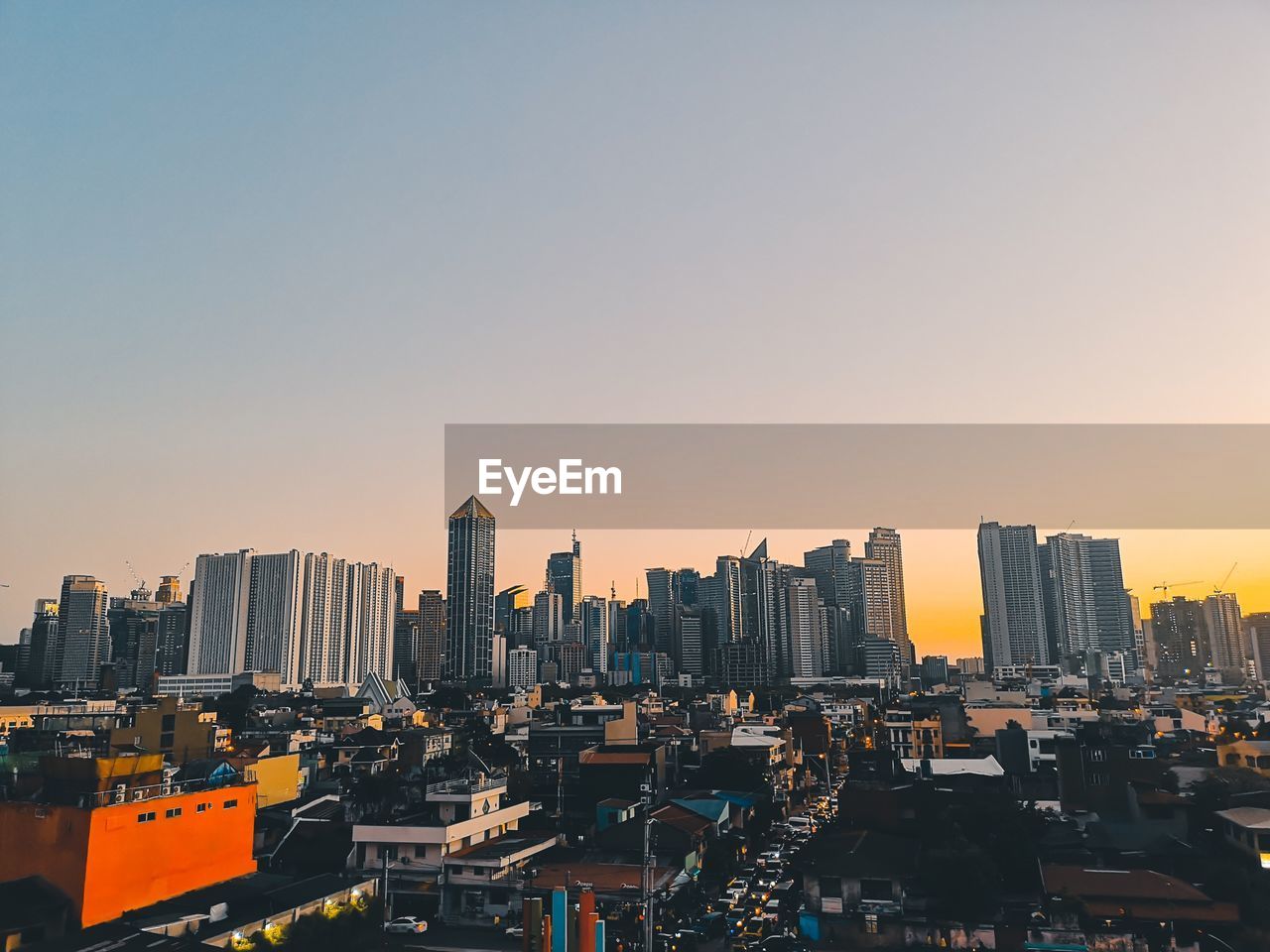 Modern buildings in city against clear sky during sunset