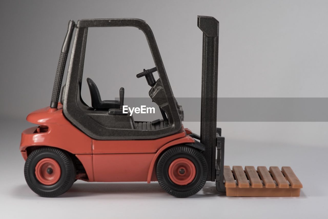 forklift truck, vehicle, transportation, land vehicle, industry, studio shot, mode of transportation, wheel, indoors, gray background, tread, forklift, gray, motor vehicle, cut out, truck, no people, business