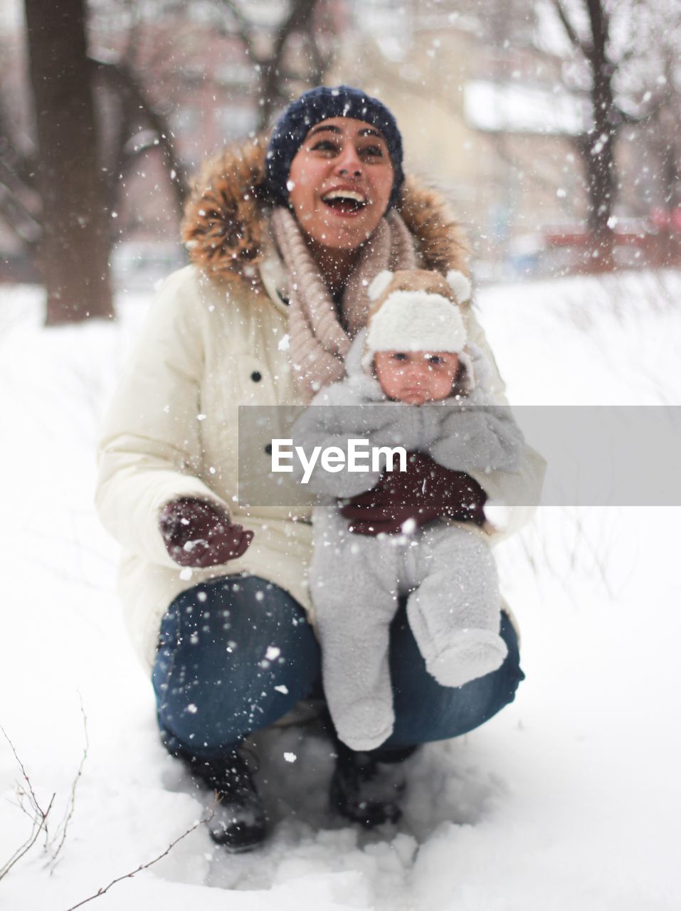 Portrait of smiling young woman and baby in snow