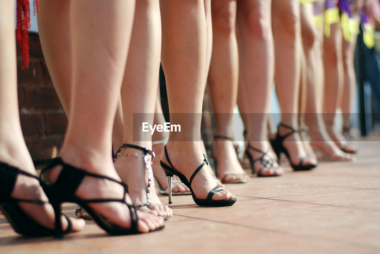 Low section of women wearing high heels while standing at fashion show