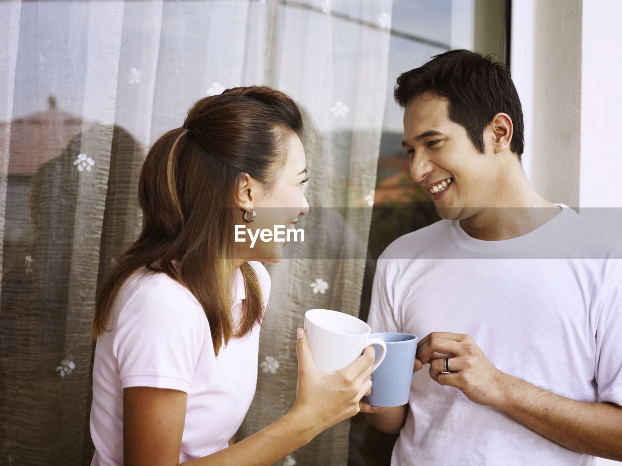 Smiling couple talking while having coffee against wall