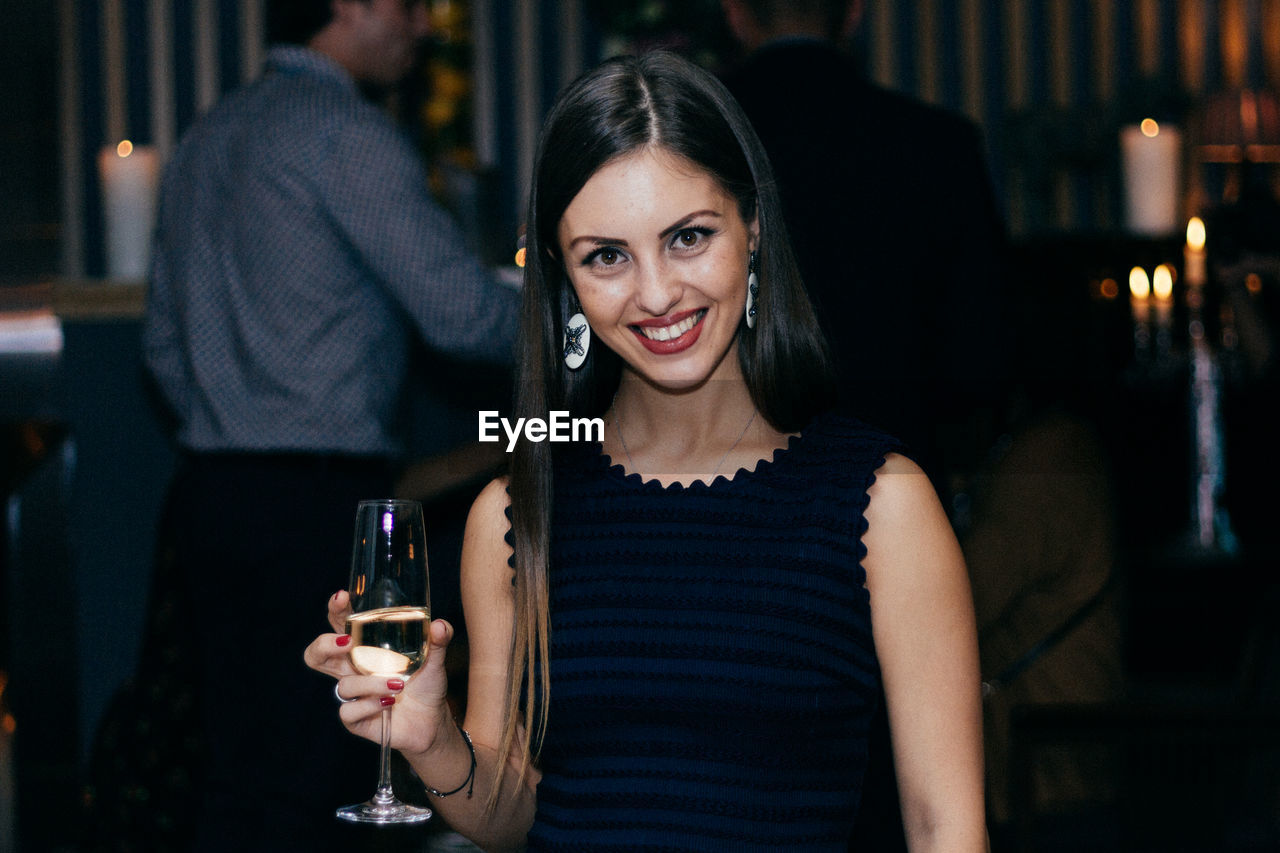 Portrait of smiling young woman having wine in party