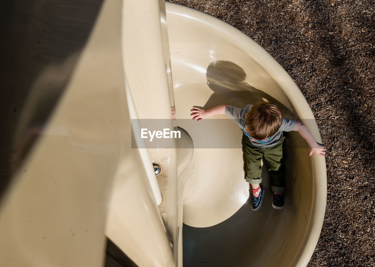 High angle view of boy playing on slide at playground