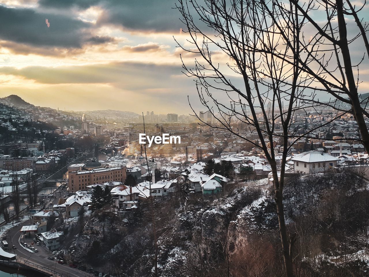 HIGH ANGLE VIEW OF BUILDINGS IN CITY AGAINST SKY AT SUNSET