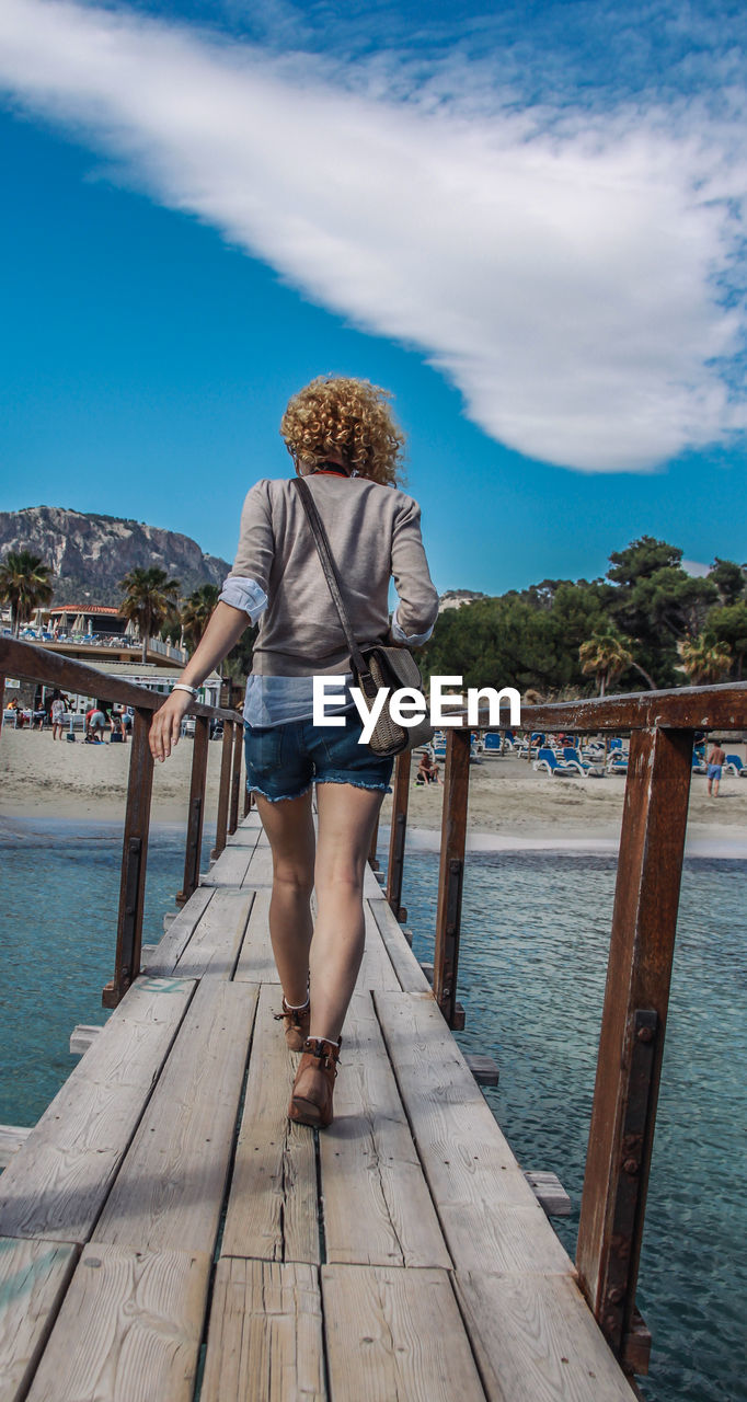 Rear view of woman walking on wooden pier