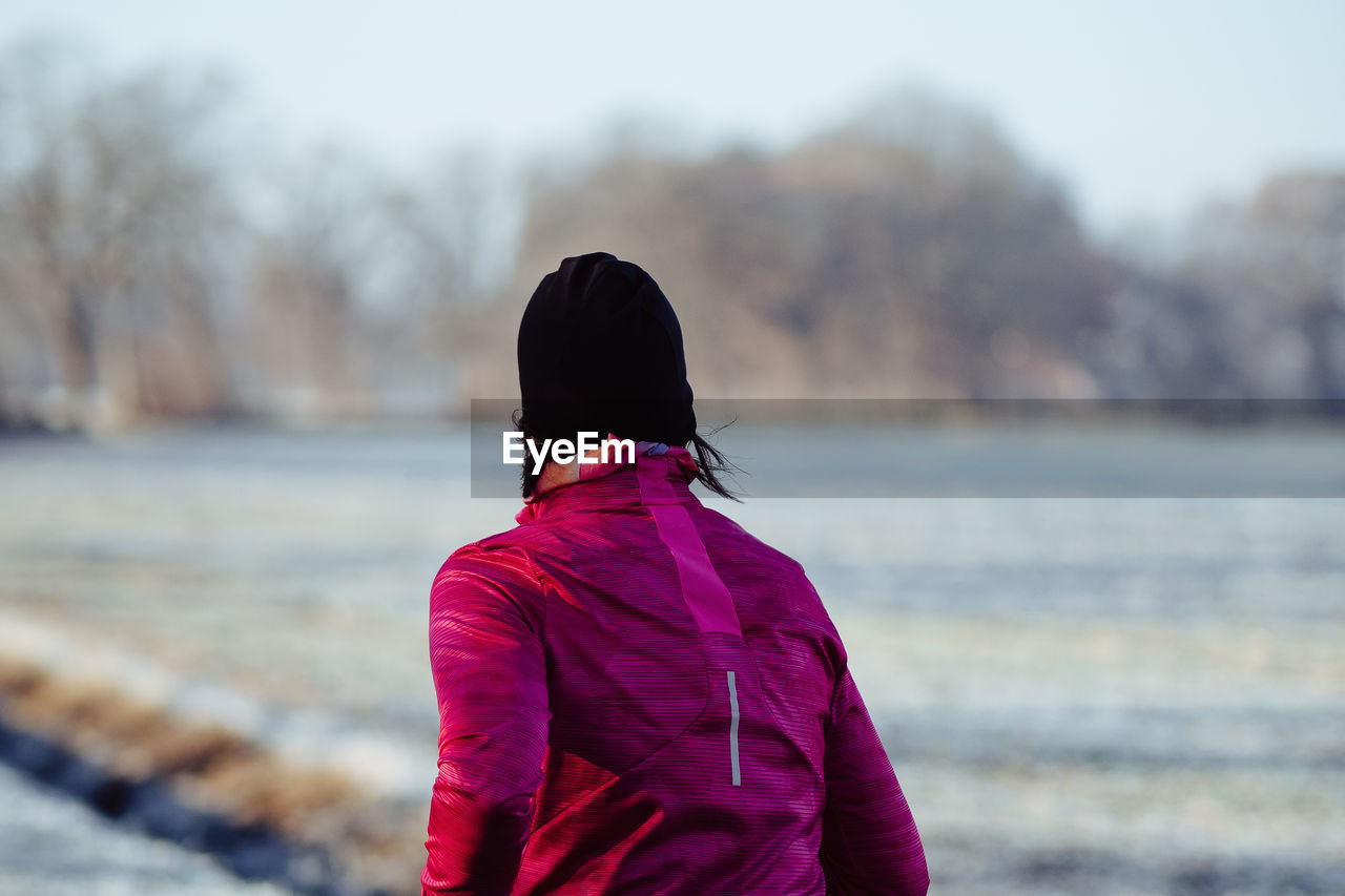 Rear view of woman walking on snow covered field