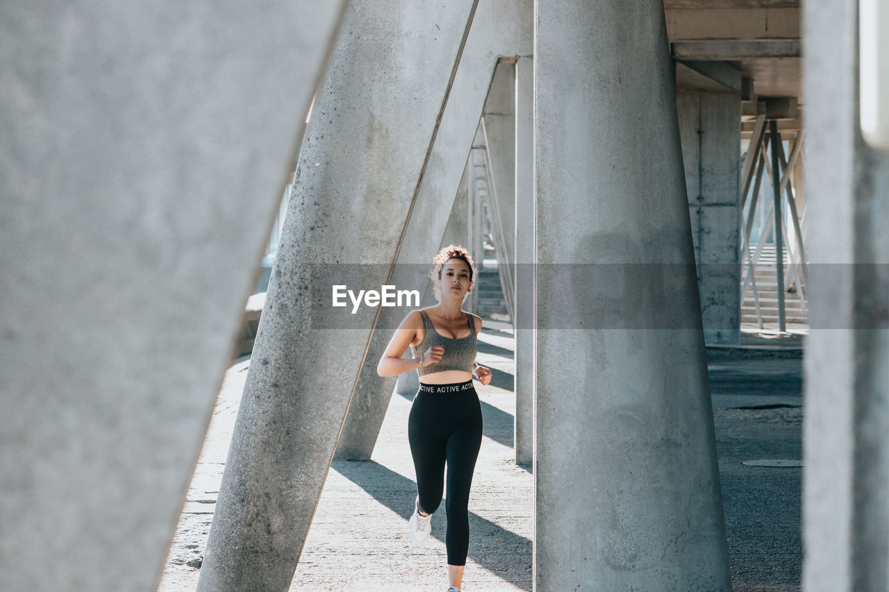 Female athlete running between column