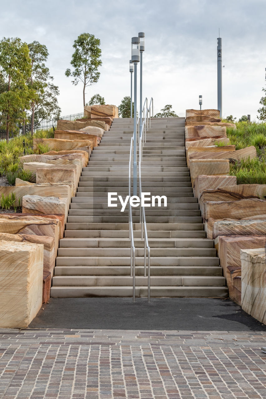 Steps amidst trees against sky