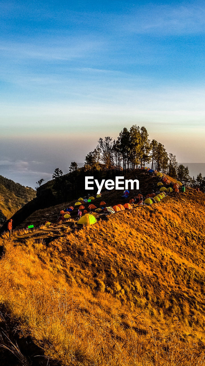 Tents on mountain against sky during sunset