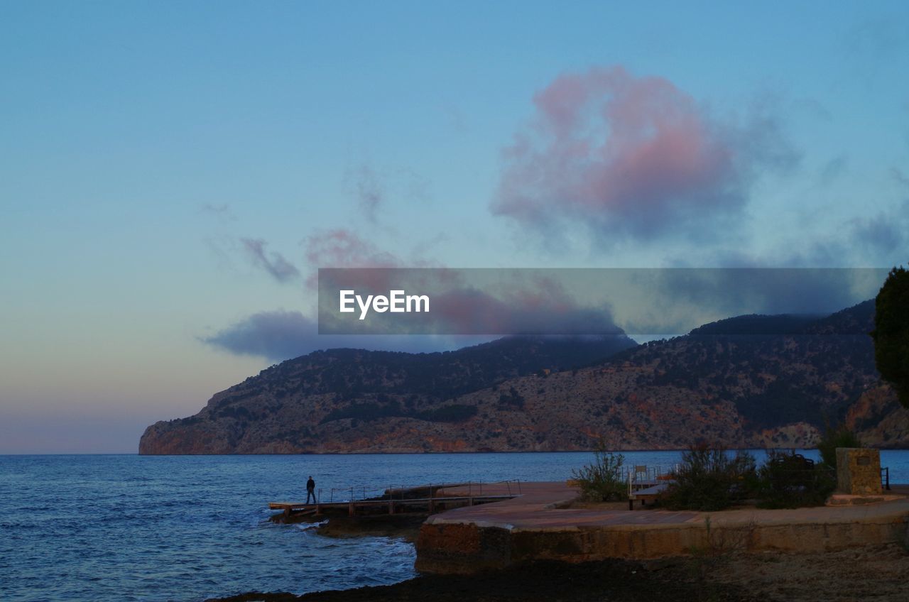SCENIC VIEW OF SEA WITH MOUNTAIN RANGE IN BACKGROUND