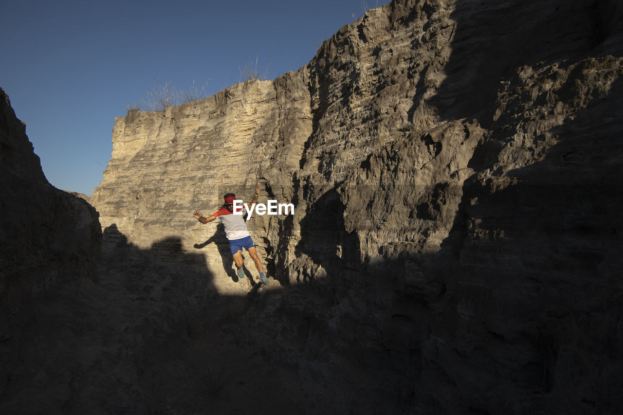 One man trail running on a small canyon with high contrast light