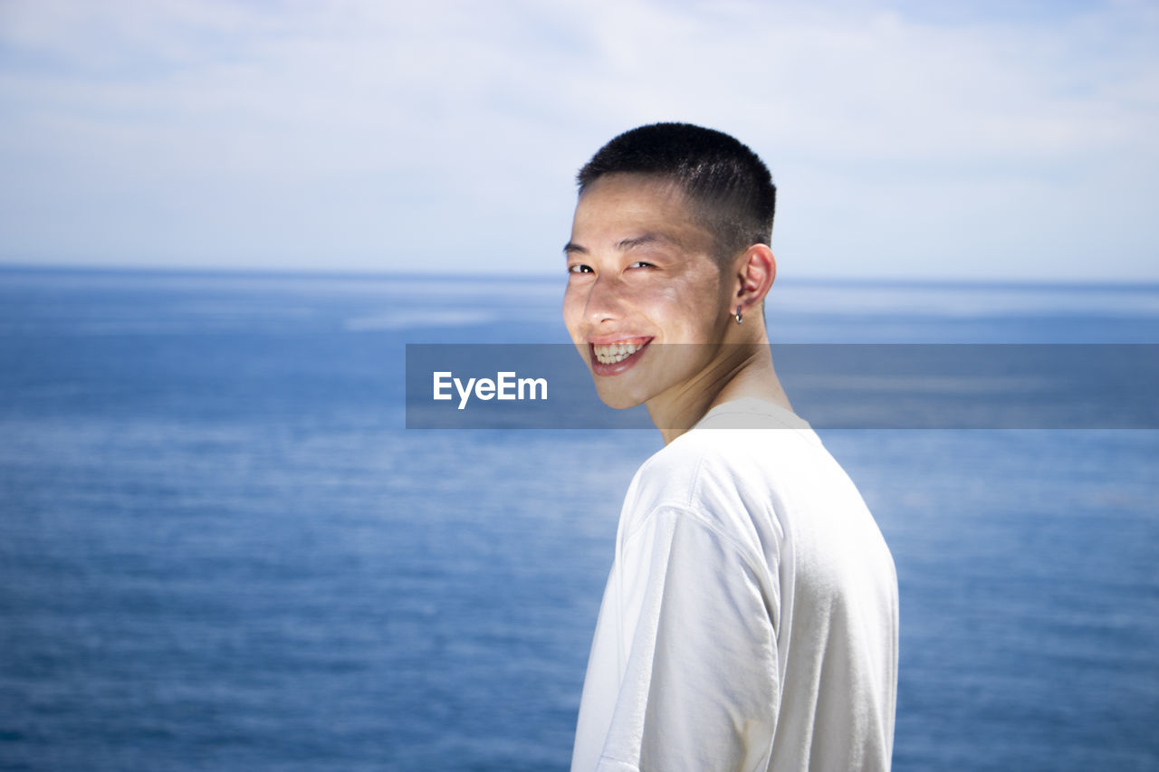 Portrait of smiling man standing in sea against sky