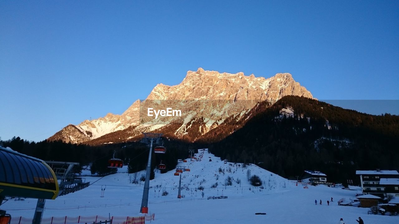 Low angle view of rocky mountains against clear blue sky on sunny day