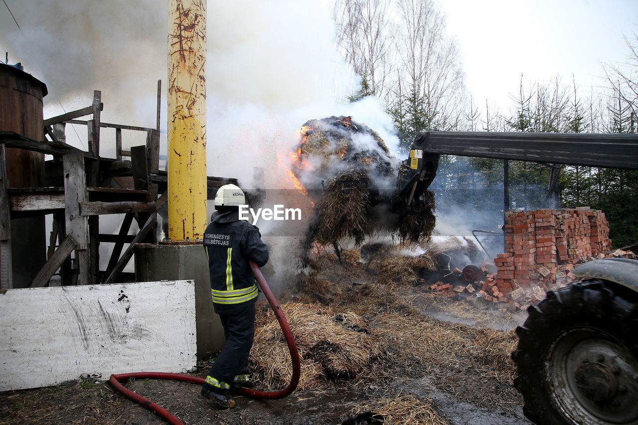 MAN WORKING ON FIRE HYDRANT AGAINST SKY