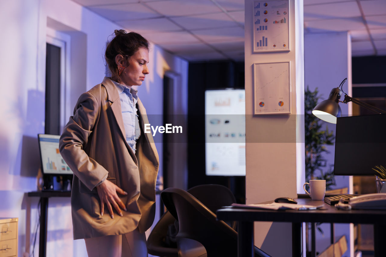 side view of young businesswoman using laptop while standing in office