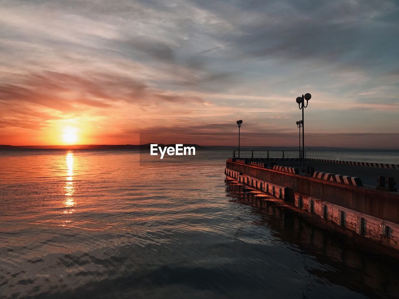 PIER OVER SEA AGAINST ORANGE SKY