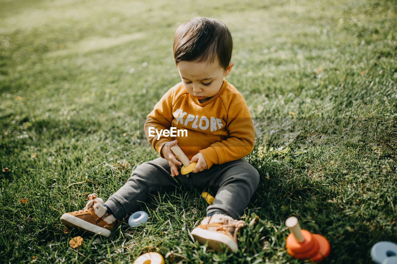 Full length of boy sitting on field