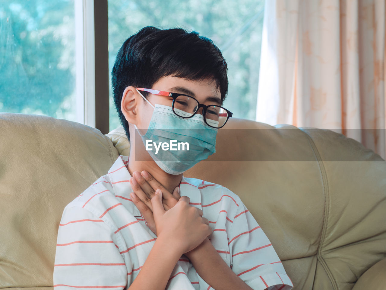 Close-up of boy wearing mask sitting on sofa