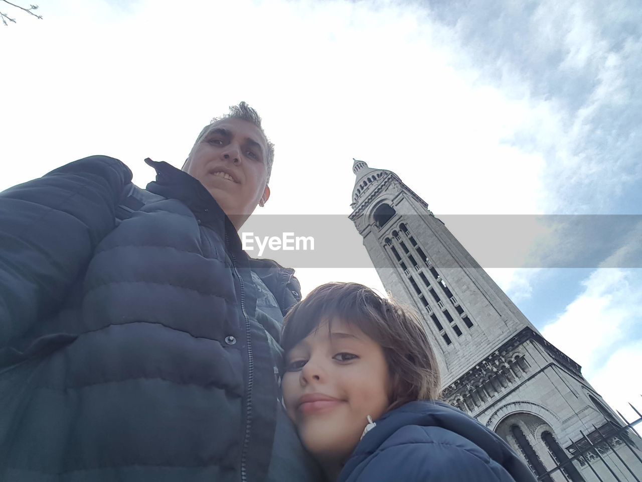 two people, sky, child, low angle view, adult, childhood, togetherness, architecture, men, women, family, cloud, portrait, day, female, nature, bonding, emotion, travel, positive emotion, built structure, parent, one parent, looking, building exterior, travel destinations, city, blue, leisure activity, outdoors, smiling, love, lifestyles, person, tourism, happiness, clothing, headshot, looking up, winter, vacation, trip