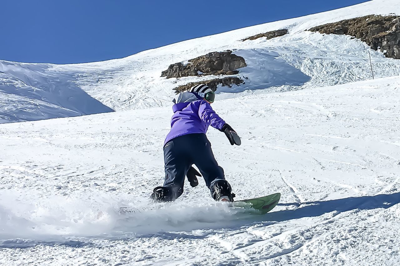Person snowboarding on mountain against sky