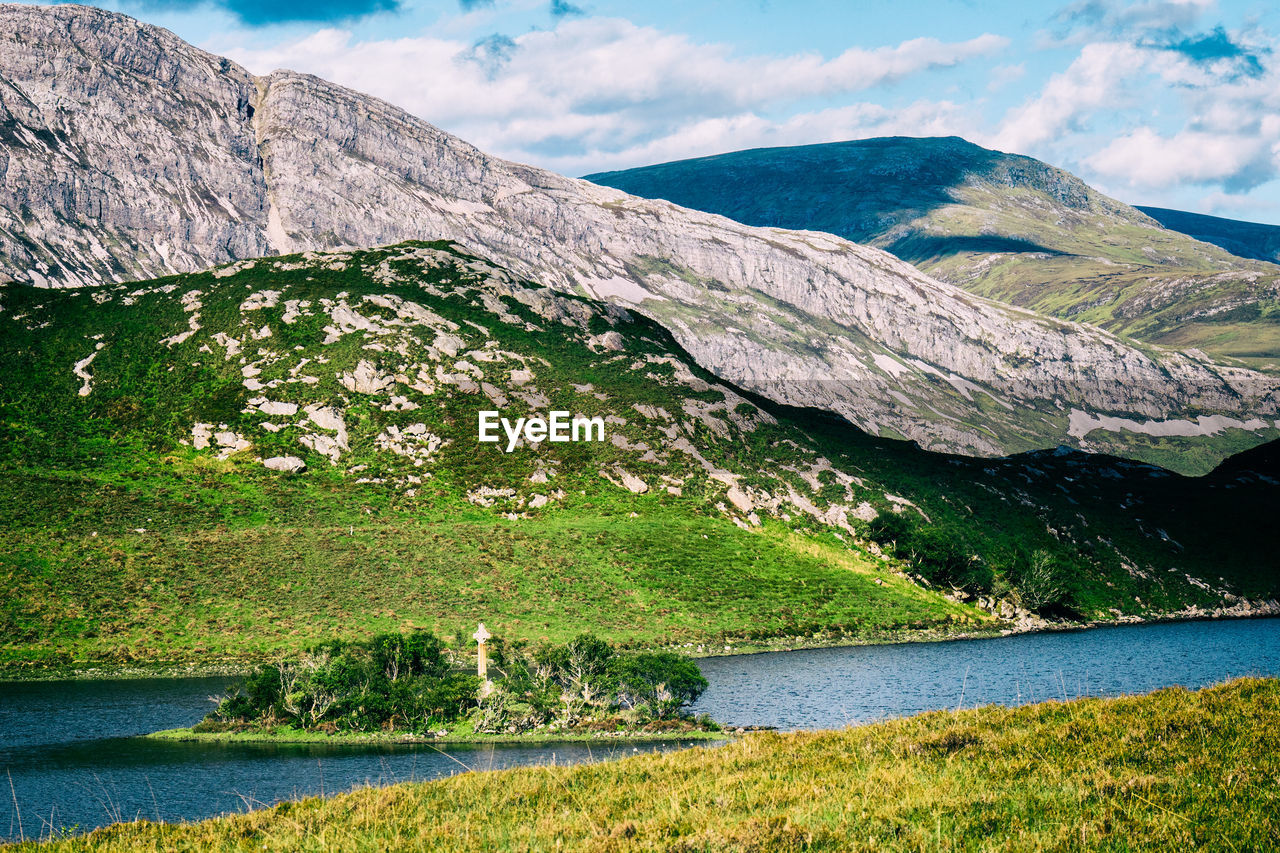 Small island with a cross on it surrounded by the vast nature of the scottish highlands