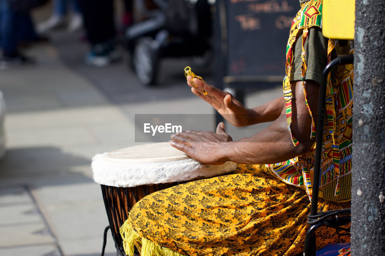 Midsection of man playing drum