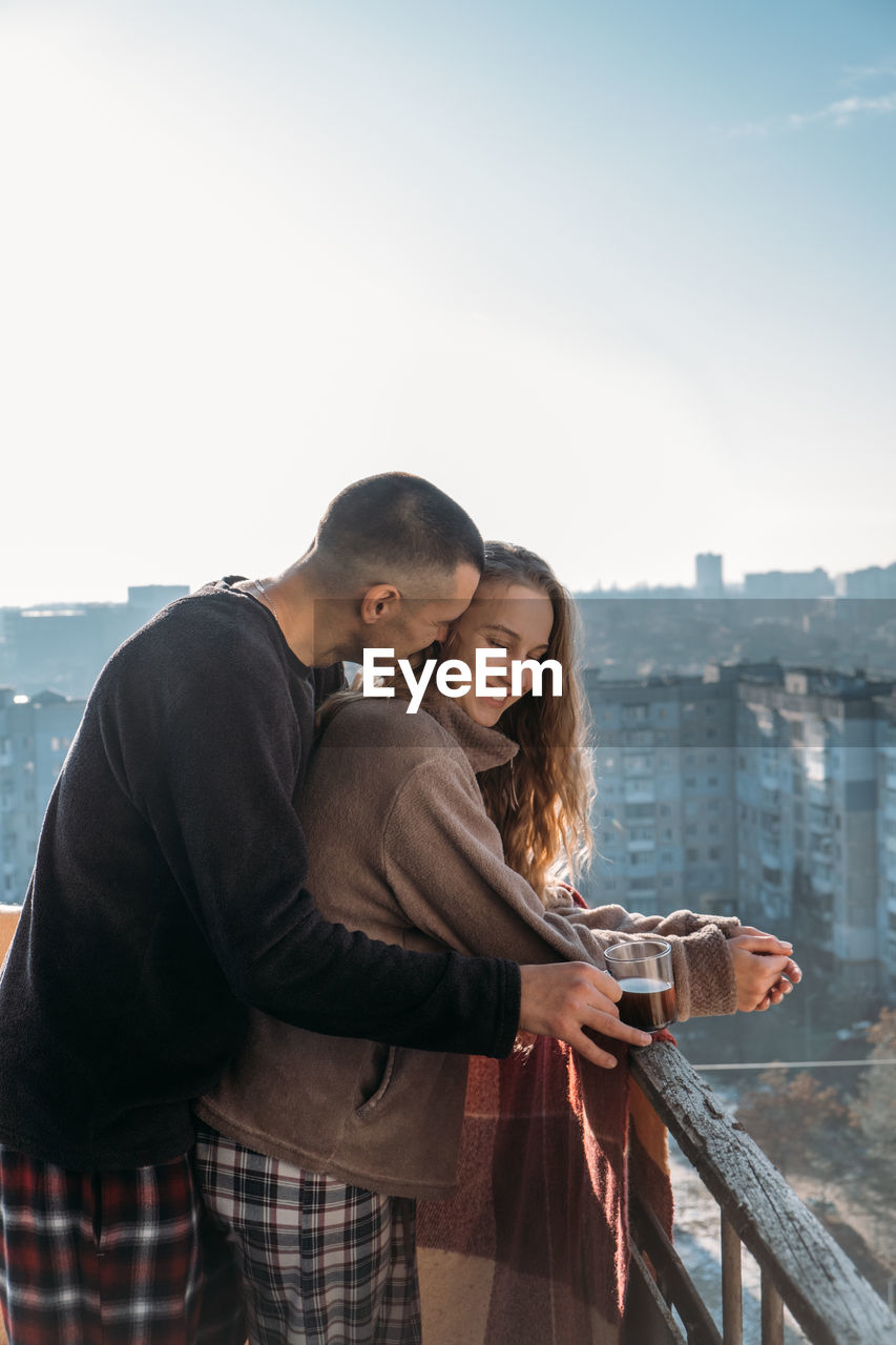 Young couple drinking coffee on the balcony of the apartment in the morning. young happy couple