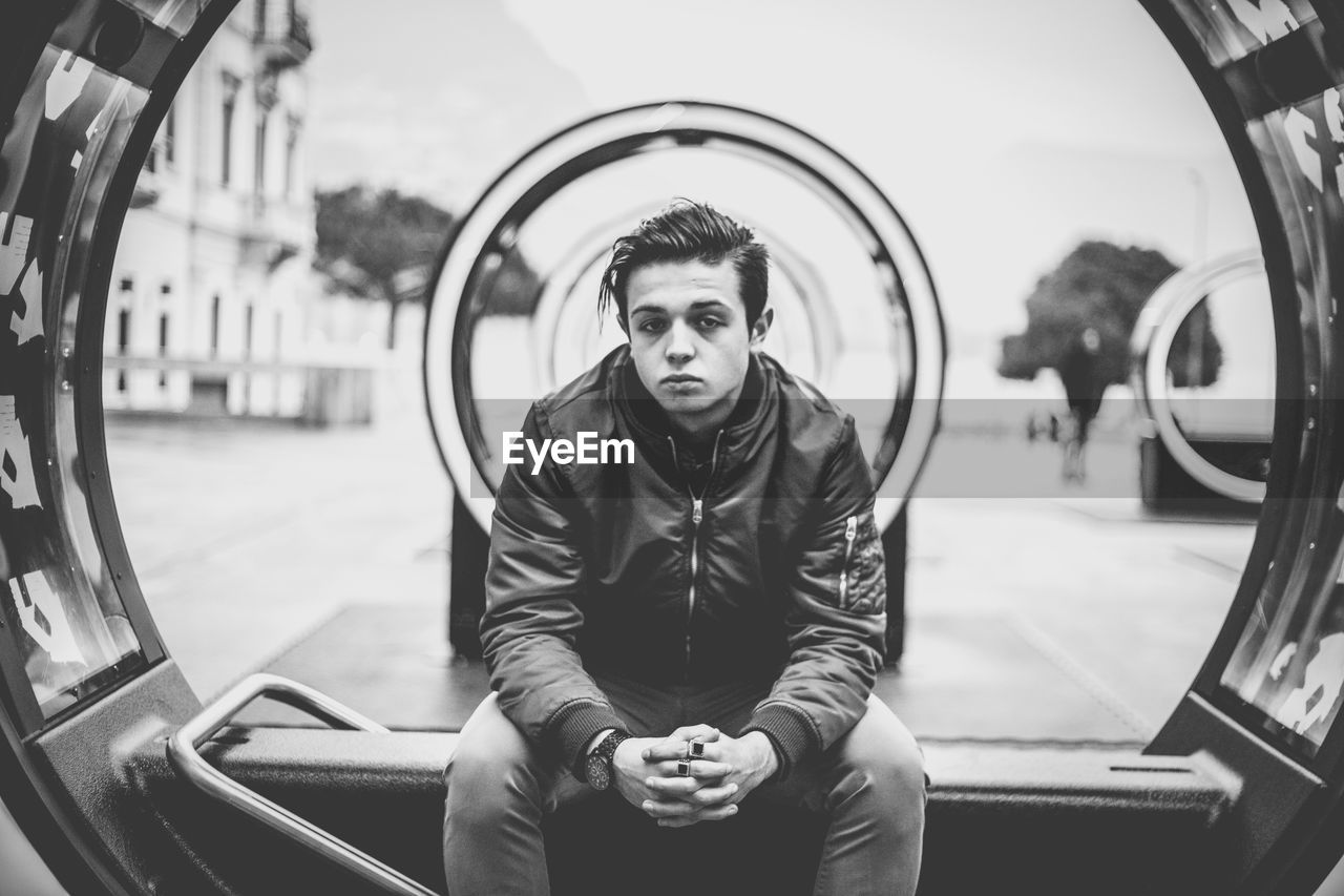 Young man sitting on sea at city street