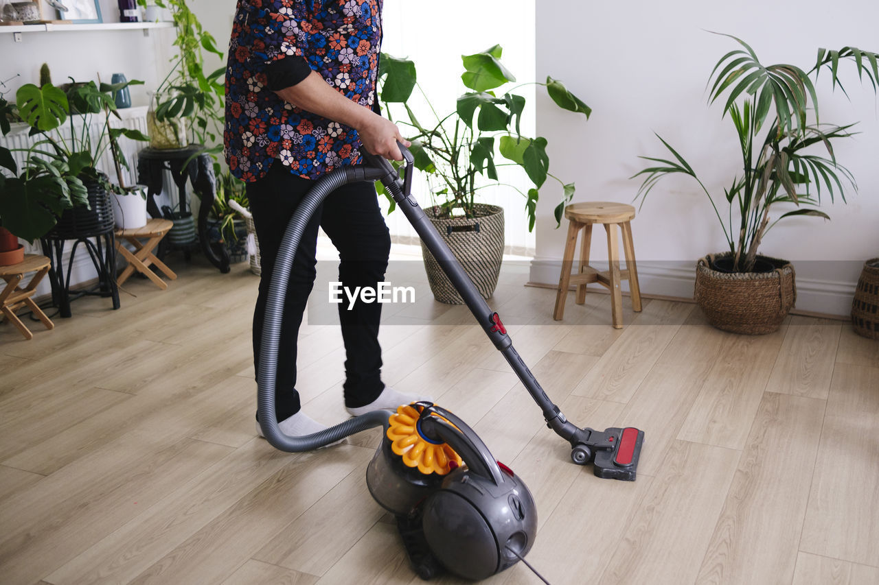Mature man cleaning with vacuum cleaner at home