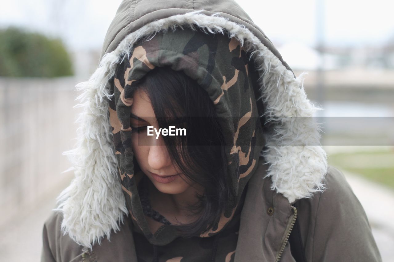 Close-up of young woman wearing hooded jacket in city