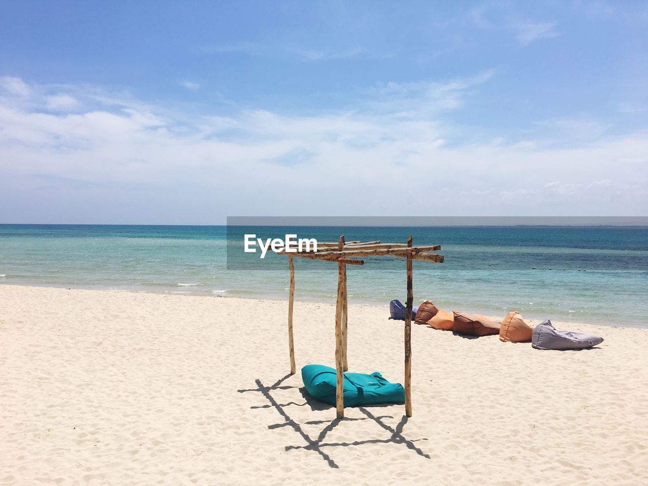 Deck chairs on beach against blue sky