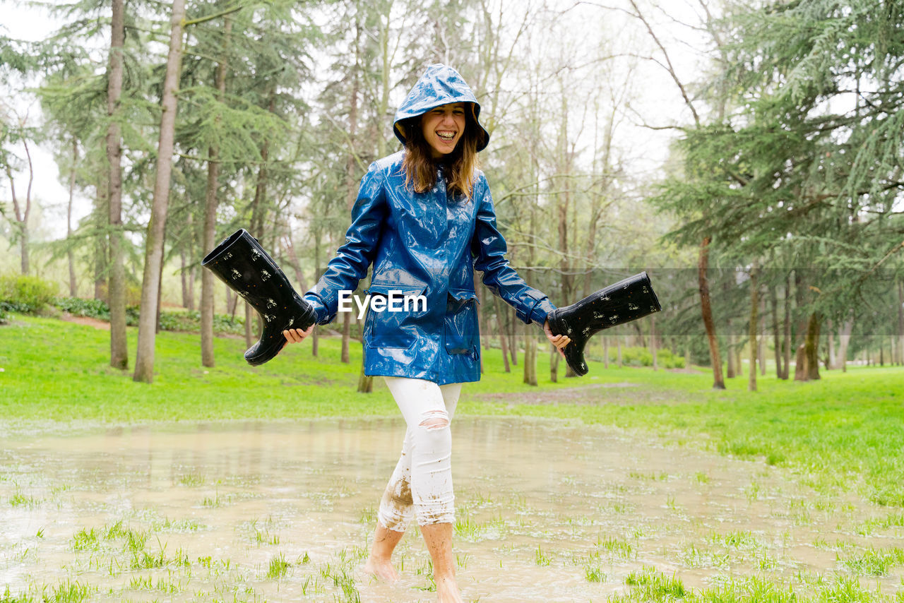 Happy woman with rubber boots walking in puddle