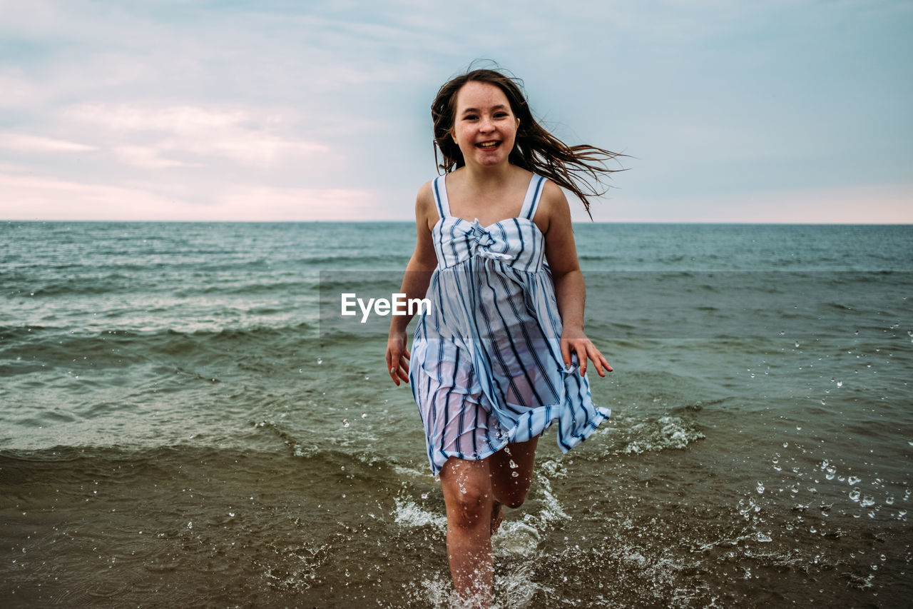 Young girl running through water in clothes in lake michigan