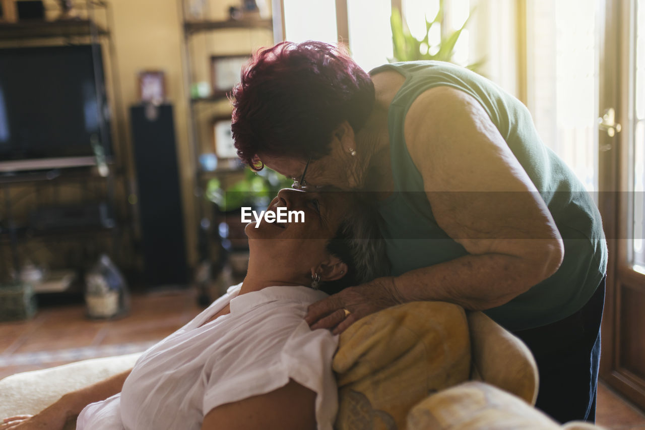 Mother kissing on daughter's forehead at home