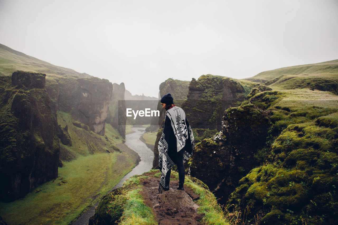 Woman standing at scenic mountains against sky