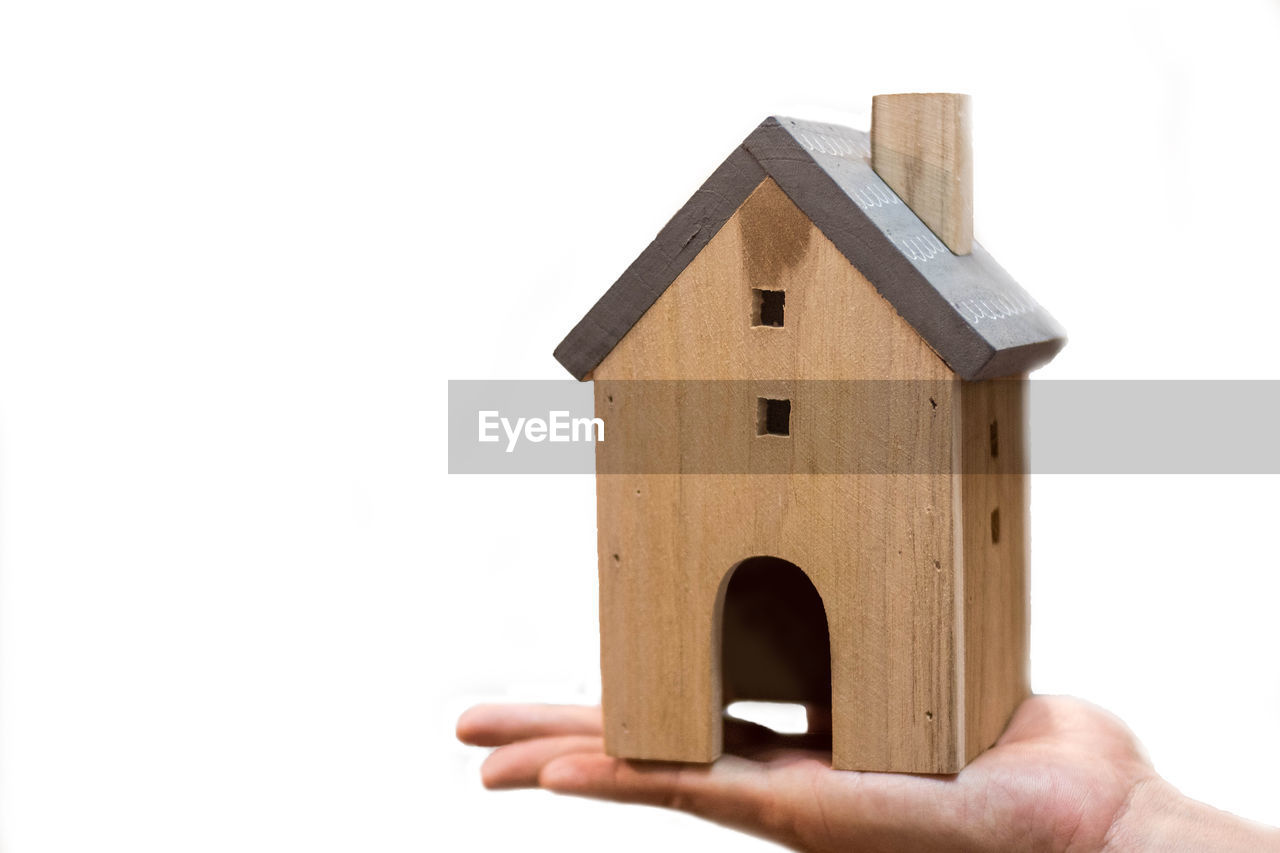 CLOSE-UP OF HAND HOLDING SMALL WOODEN BUILDING