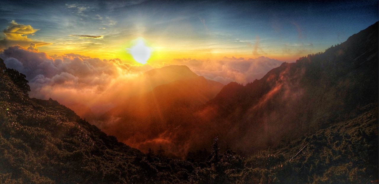 SUN SHINING THROUGH CLOUDS OVER MOUNTAINS