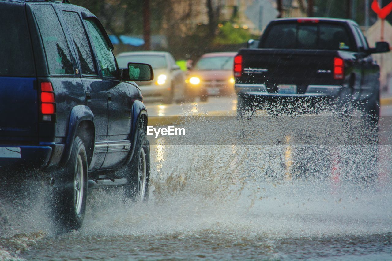 Cars splashing water on road in rainy season