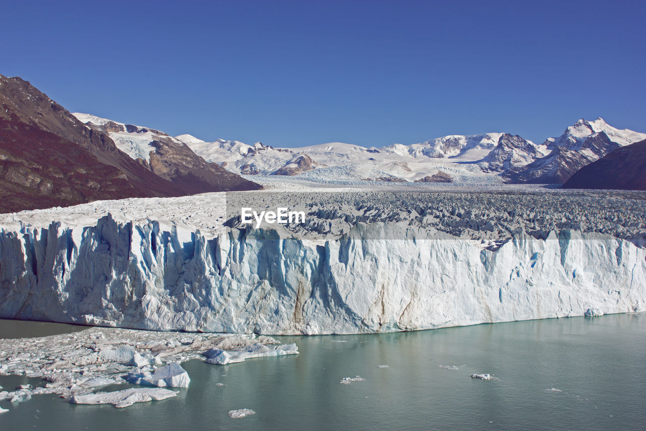 Scenic view of glacier against clear blue sky