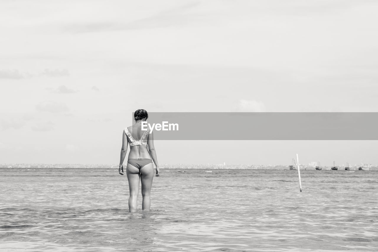 Woman standing in sea against sky