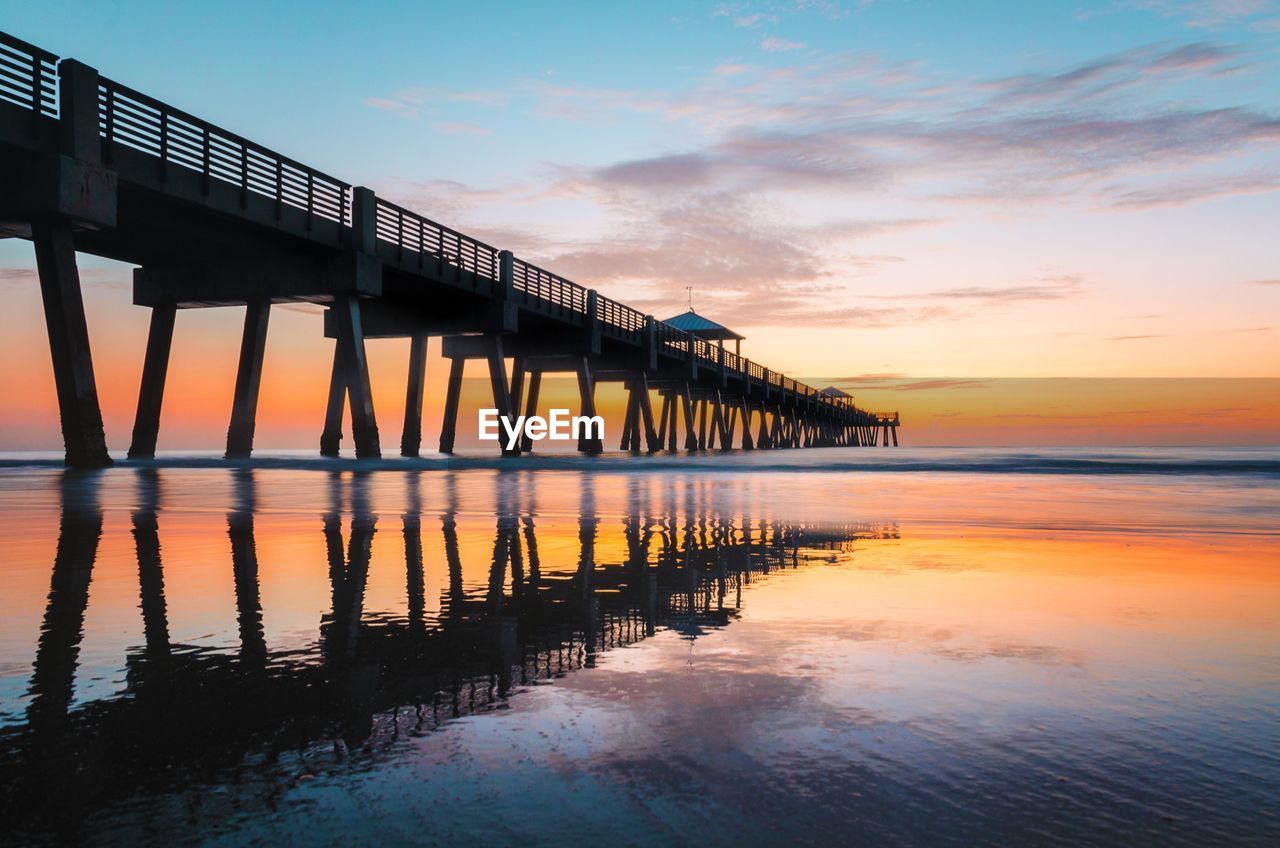 Pier on sea against sky at sunset