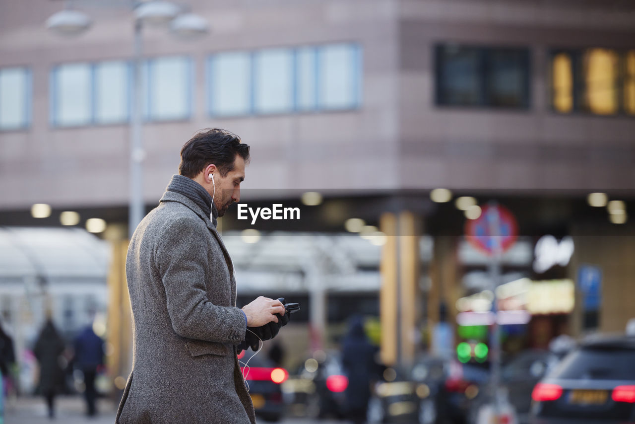 Businessman using phone outdoors in city