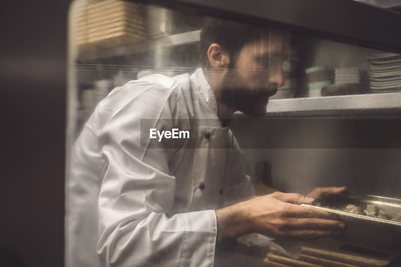 Male chef baking mushroom in commercial kitchen