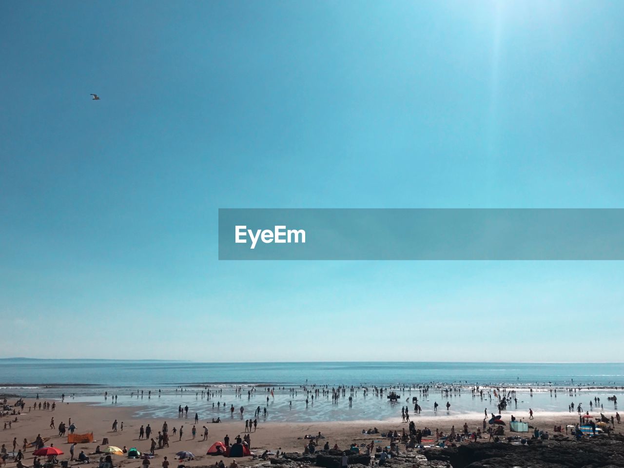 People at beach against blue sky